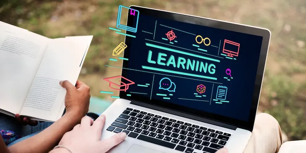 Person reading notes beside a laptop showing a Learning graphic