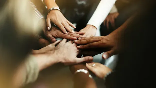 Group of people stacking their hands together in unity