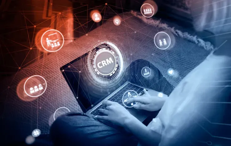 Person using a laptop with a glowing CRM icon and network graphics