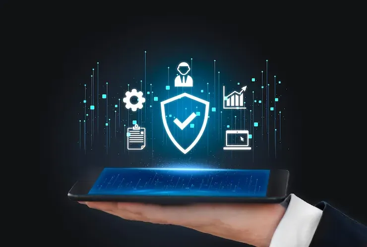 Hand holding a tablet with a glowing security shield and data icons above it