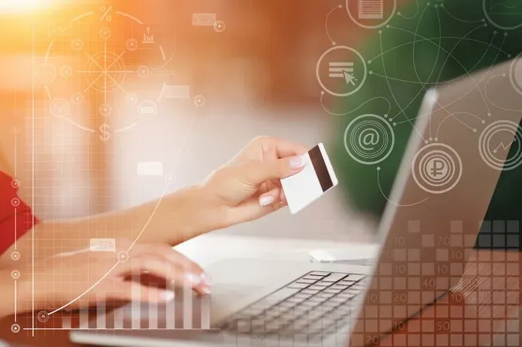 Person holding a bank card while typing on a laptop to pay online