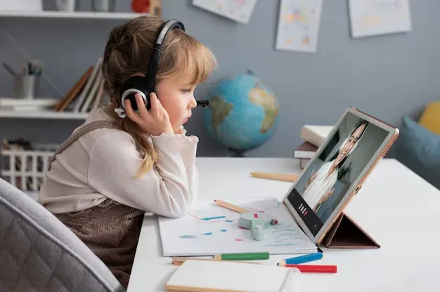 Young girl with headphones in an online lesson on a tablet