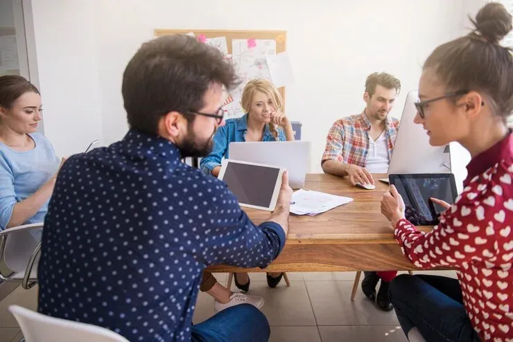 Adults collaborating with tablets and laptops around a table