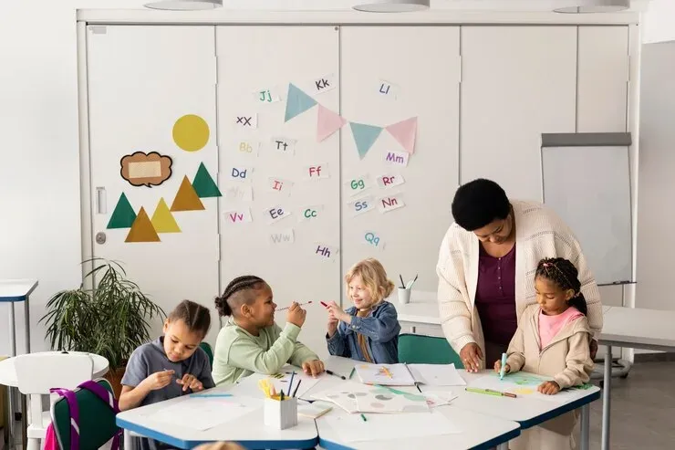 Teacher helping a diverse group of young children draw at a table