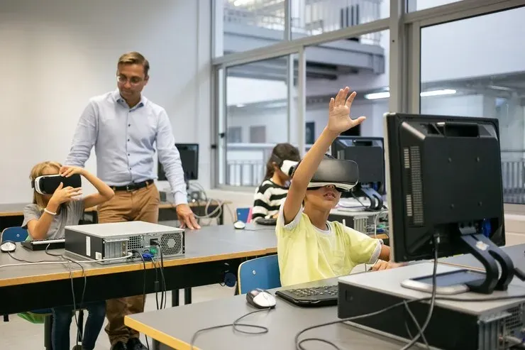 Teacher watching students use VR headsets at classroom computers