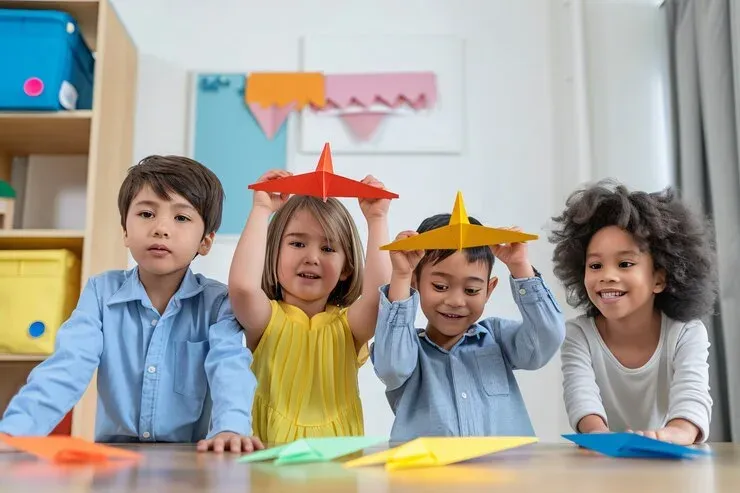 Young children playing with colourful paper airplanes at a table