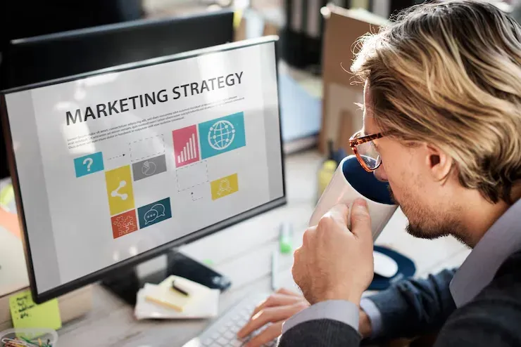 Man drinking coffee in front of a screen titled Marketing Strategy